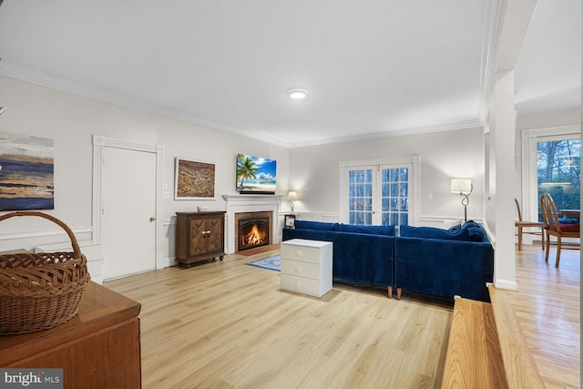 living room featuring a warm lit fireplace, ornamental molding, and wood finished floors