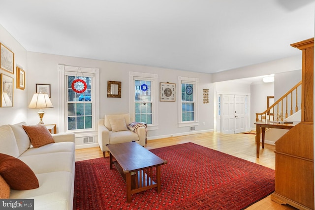 living room with visible vents, stairway, baseboards, and wood finished floors