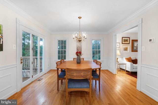 dining room with a wainscoted wall, light wood finished floors, and visible vents