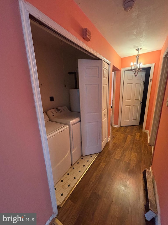 laundry area featuring laundry area, washer and clothes dryer, wood finished floors, an inviting chandelier, and water heater