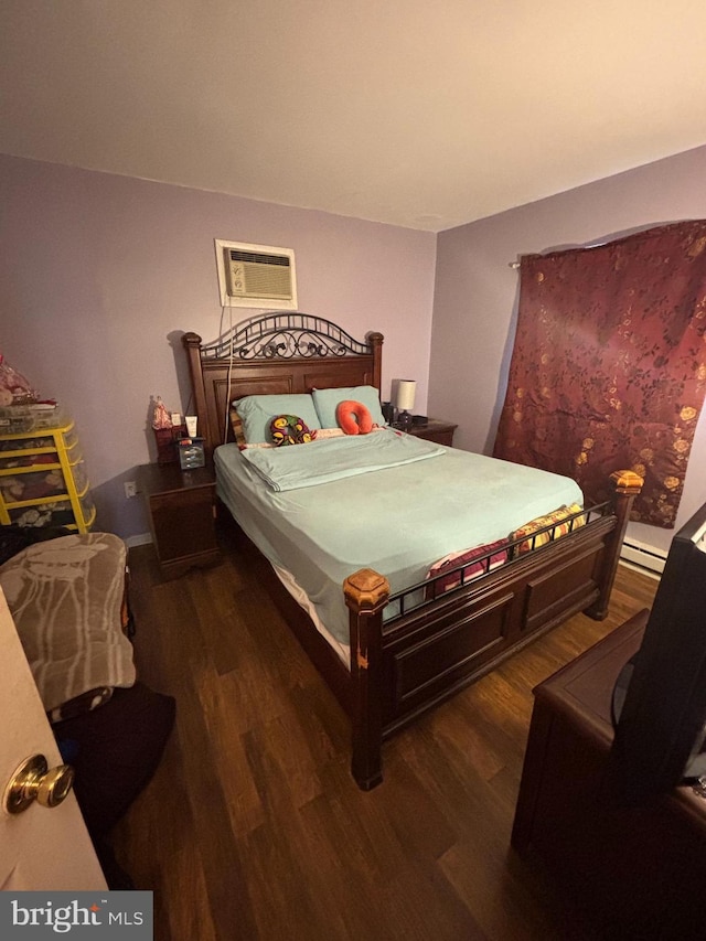 bedroom with a baseboard heating unit, a wall unit AC, and wood finished floors