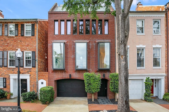 view of property featuring driveway, a garage, and brick siding