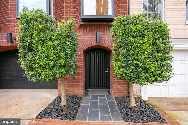 property entrance with a garage and brick siding