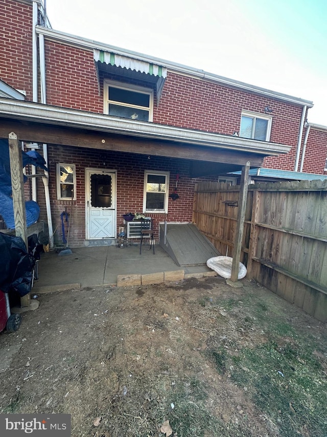 rear view of property featuring brick siding and fence