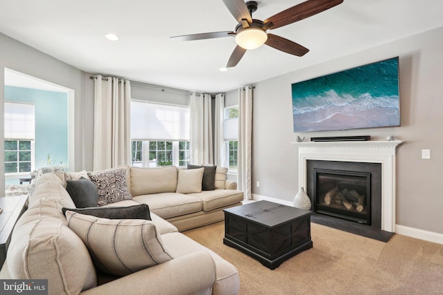 living room with recessed lighting, light carpet, a fireplace with flush hearth, a ceiling fan, and baseboards