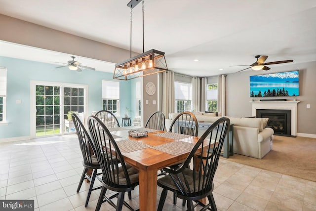 dining space featuring light tile patterned floors, recessed lighting, light colored carpet, baseboards, and a glass covered fireplace