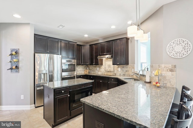 kitchen featuring decorative backsplash, light stone counters, a peninsula, under cabinet range hood, and black appliances