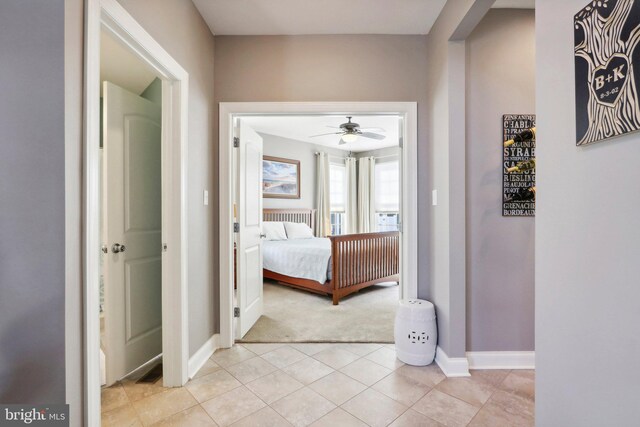 corridor with baseboards and light tile patterned flooring