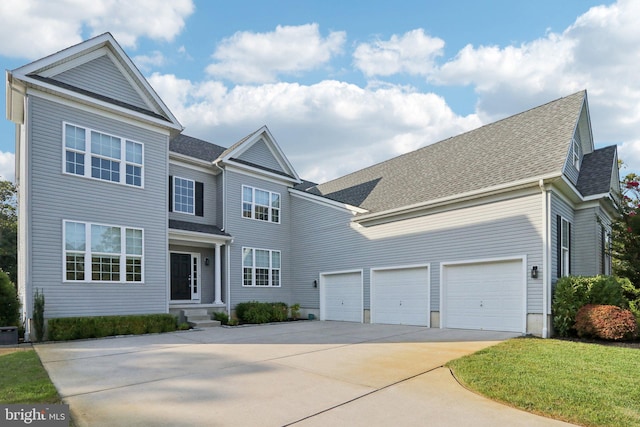 traditional home with driveway, a shingled roof, and an attached garage