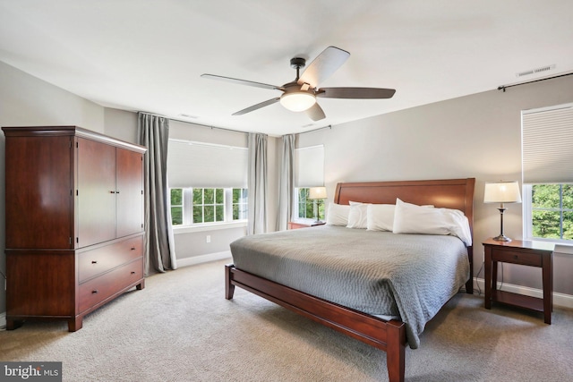 bedroom featuring light carpet, multiple windows, visible vents, and baseboards