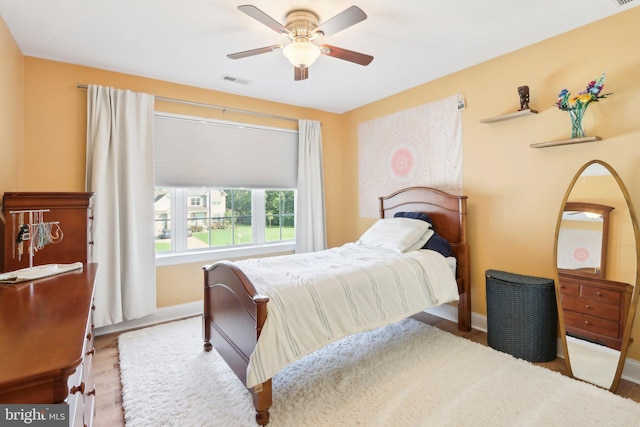 bedroom featuring ceiling fan, wood finished floors, visible vents, and baseboards