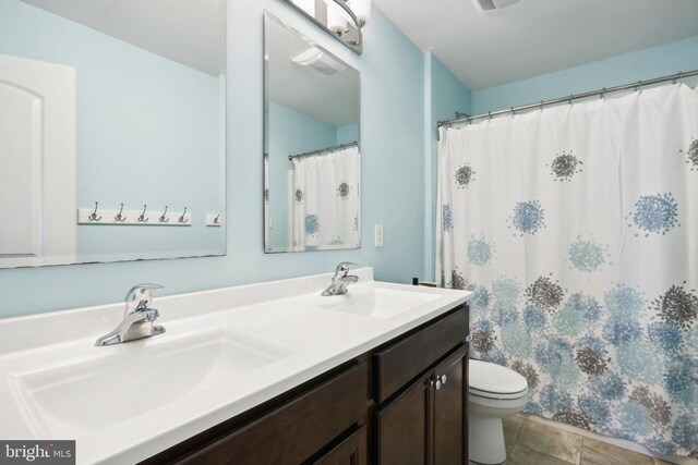 full bathroom featuring double vanity, a sink, and toilet