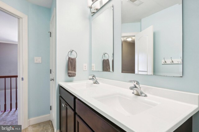 full bathroom with double vanity, a sink, visible vents, and baseboards