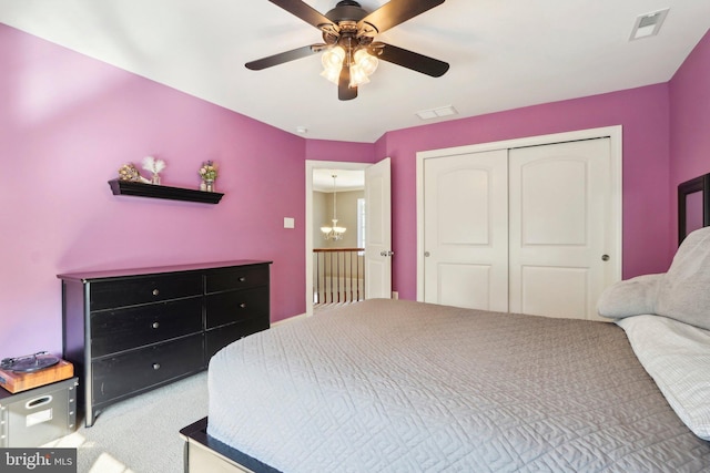 carpeted bedroom featuring a closet, visible vents, and ceiling fan with notable chandelier