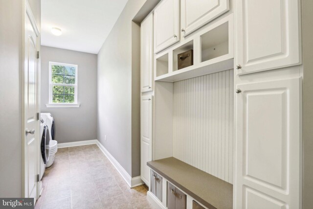 mudroom with light tile patterned floors, washing machine and clothes dryer, and baseboards