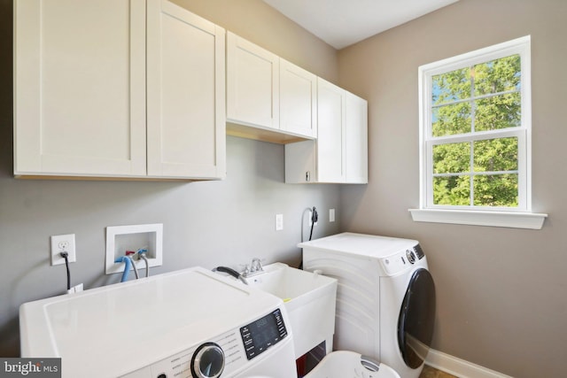 clothes washing area featuring cabinet space, baseboards, a sink, and washing machine and clothes dryer