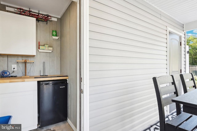 interior space featuring concrete flooring, refrigerator, and indoor wet bar