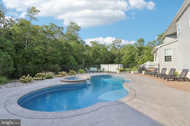 view of pool with a pool with connected hot tub, a patio area, and fence