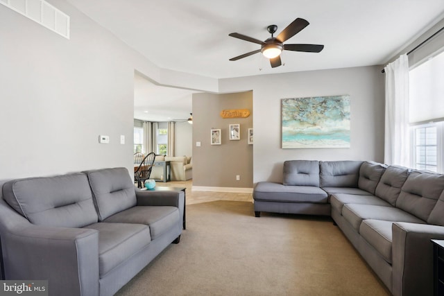 living room featuring light colored carpet, a healthy amount of sunlight, visible vents, and ceiling fan