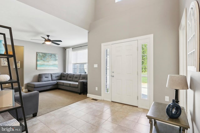 foyer with light tile patterned floors, a ceiling fan, and baseboards