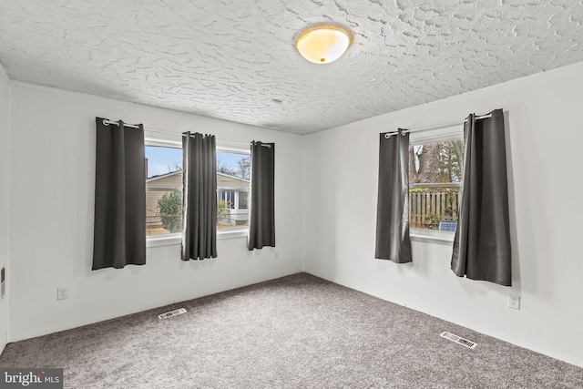 carpeted empty room with a textured ceiling and visible vents