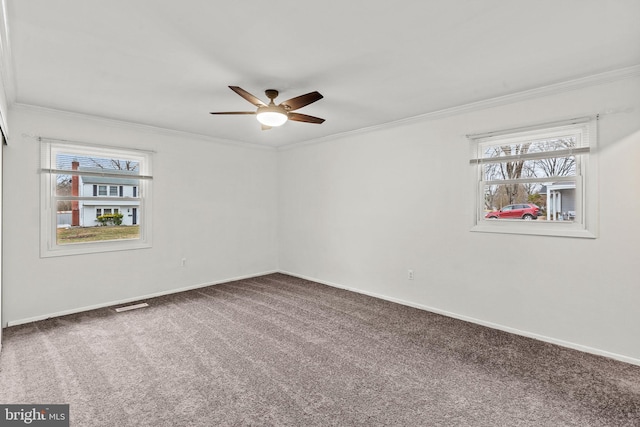 empty room with visible vents, ornamental molding, a ceiling fan, carpet flooring, and baseboards