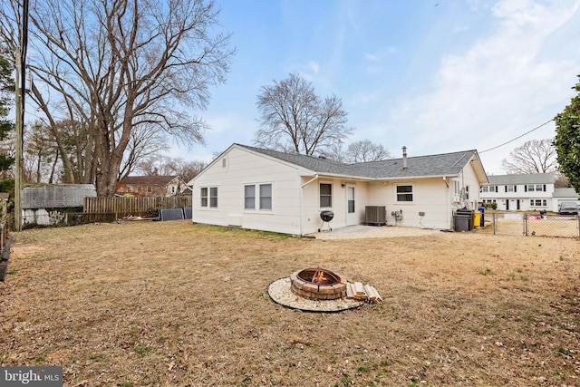 rear view of house featuring a lawn, central AC unit, an outdoor fire pit, a patio area, and a fenced backyard