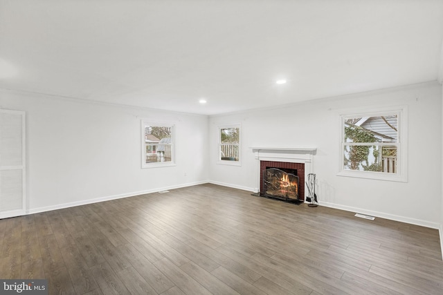 unfurnished living room featuring a healthy amount of sunlight, dark wood-style floors, a fireplace, and baseboards