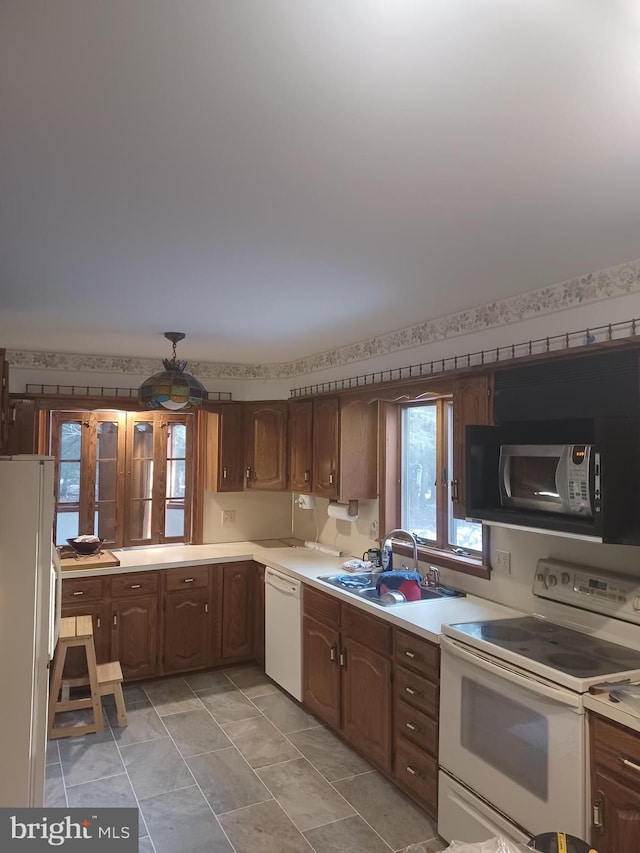 kitchen with white appliances, light countertops, and a sink