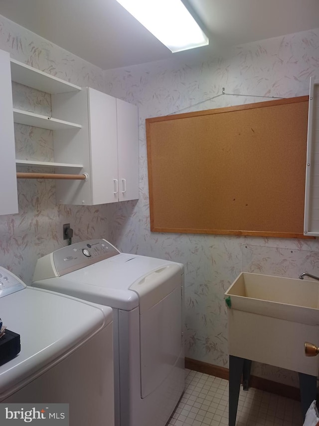 laundry area featuring wallpapered walls, light tile patterned floors, cabinet space, and independent washer and dryer