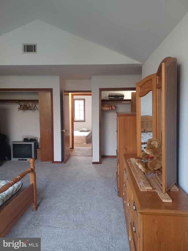 bedroom with vaulted ceiling, visible vents, and light colored carpet