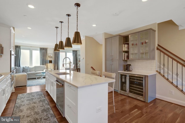 kitchen featuring a sink, open floor plan, dark wood-style flooring, a kitchen breakfast bar, and a kitchen island with sink