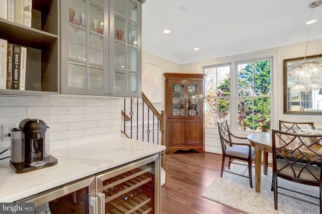 interior space with dark wood-type flooring, decorative light fixtures, tasteful backsplash, wine cooler, and crown molding