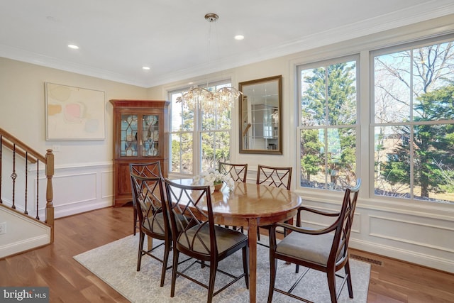 dining room with visible vents, a healthy amount of sunlight, stairway, and wood finished floors