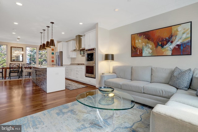 living room featuring recessed lighting, a chandelier, dark wood-style floors, and crown molding