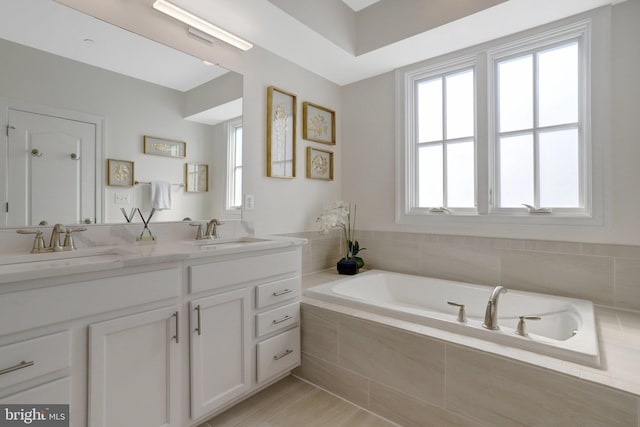 full bathroom with double vanity, plenty of natural light, a bath, and a sink