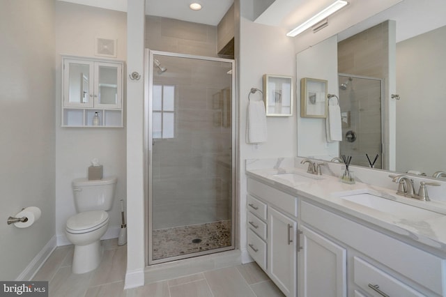 bathroom featuring double vanity, a stall shower, toilet, and a sink