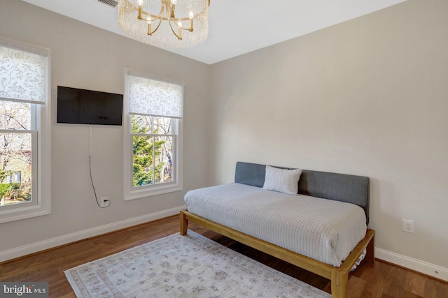 bedroom featuring a chandelier, baseboards, and wood finished floors