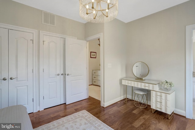 bedroom featuring visible vents, an inviting chandelier, baseboards, and wood finished floors