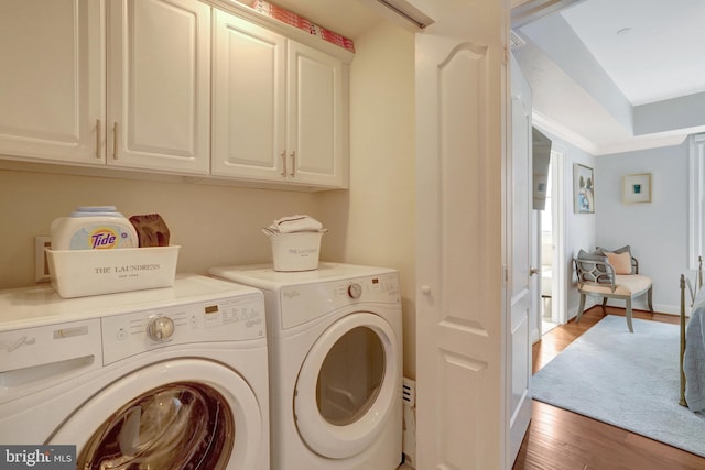 clothes washing area with light wood-style flooring, cabinet space, and washing machine and dryer