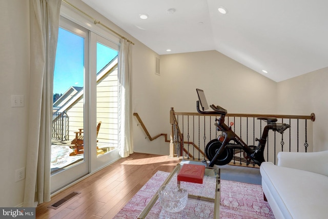 workout room with visible vents, a healthy amount of sunlight, wood finished floors, and vaulted ceiling