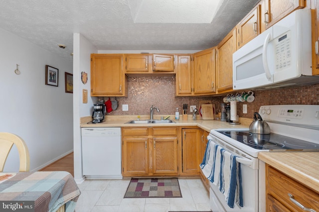 kitchen featuring white appliances, light countertops, and a sink