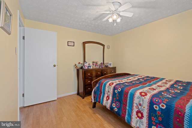 bedroom with ceiling fan, a textured ceiling, baseboards, and wood finished floors