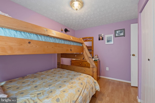 bedroom featuring a textured ceiling, baseboards, and wood finished floors