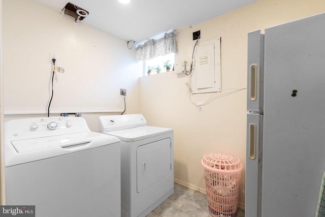 clothes washing area featuring laundry area, washing machine and dryer, electric panel, and baseboards