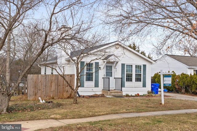 bungalow-style home with a chimney, fence, and a front yard