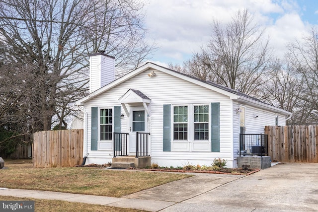 bungalow-style home with a chimney and fence