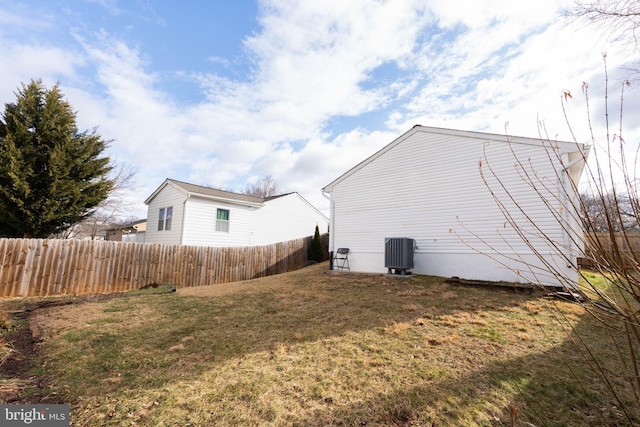 view of side of home with central air condition unit, fence, and a yard