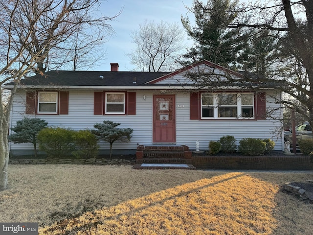 view of front facade featuring a chimney and a front lawn