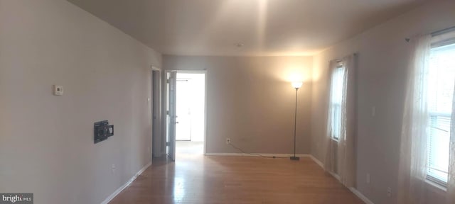 corridor featuring light wood-type flooring and baseboards